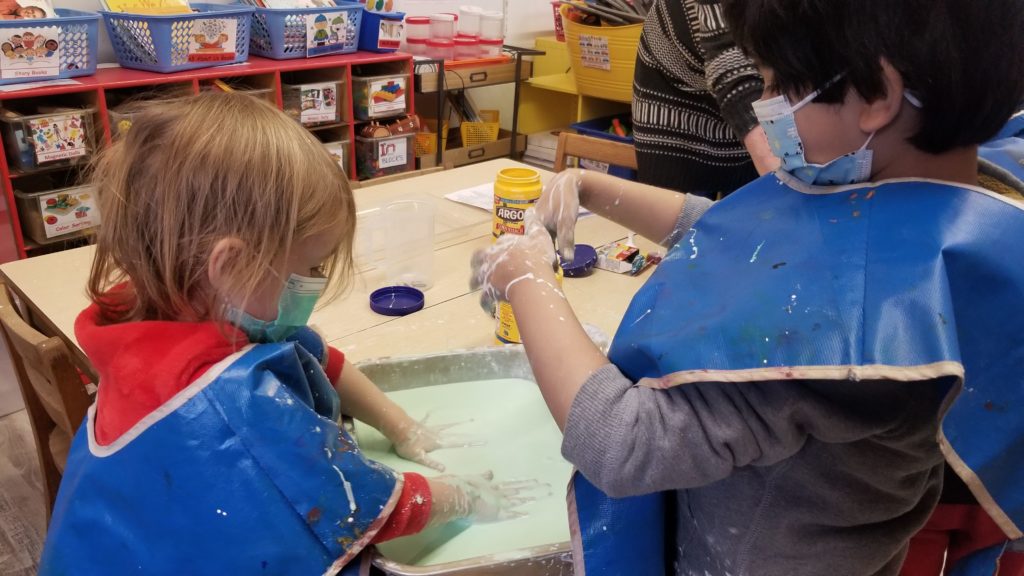 Two students experimenting with a greenish goo.